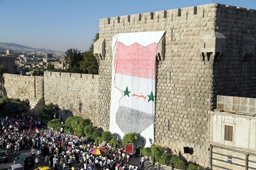 Plusieurs milliers de personnes ont assisté à la fixation sur le mur de la citadelle d'une toile géante reproduisant une carte tricolore de la Syrie